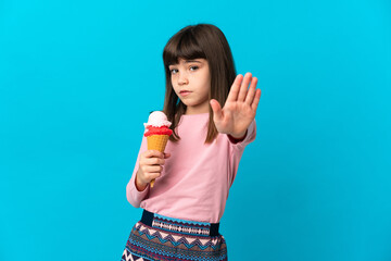 Little girl with a cornet ice cream isolated on blue background making stop gesture and disappointed