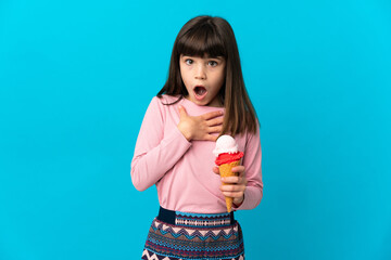 Little girl with a cornet ice cream isolated on blue background surprised and shocked while looking right