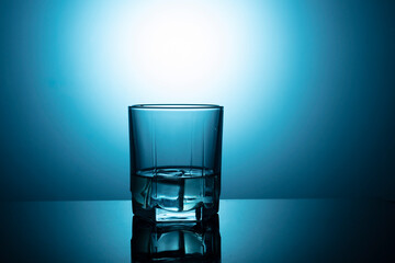 glass of water on the table on a blue background with ice cubes