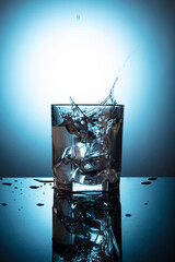 glass of water on the table on a blue background with ice cubes