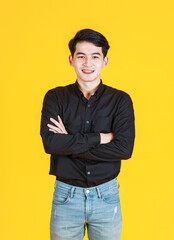 Fototapeta premium Portrait studio shot of Asian young man professional successful male businessman in casual black shirt standing smiling look at camera on yellow background