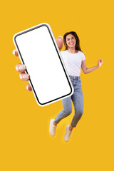 Woman showing white empty smartphone screen and jumping up high