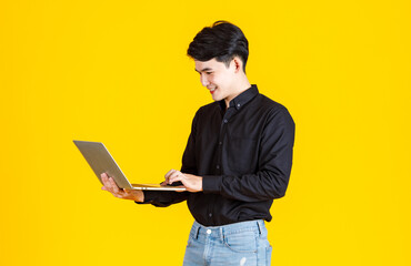 Portrait closeup studio shot of Asian man happy male businessman model in casual outfit standing holding laptop computer for advertising on yellow background