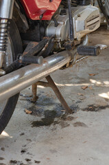An old motorcycle with oil leaking onto the ground.