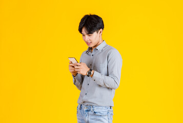 Studio shot of millennial Asian thoughtful doubtful curious male fashion model in stylish fashionable casual outfit standing crossed arm holding hand and finger on head thinking on yellow background