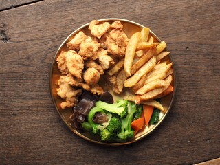 Top view dish of fried chicken, fried potato, boiled broccoli, carrot and ear mushroom
