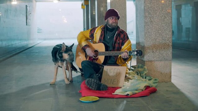 Underpass with an almsman and his dog playing the guitar