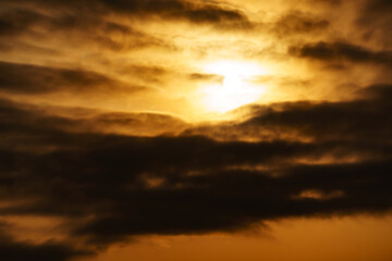 Obraz premium dramatic cloudy sky at sunset as a background, golden color, sun and dark silhouettes of clouds