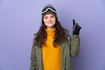 Teenager Russian girl with snowboarding glasses isolated on purple background pointing up a great idea