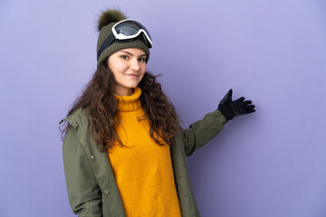 Teenager Russian girl with snowboarding glasses isolated on purple background extending hands to...