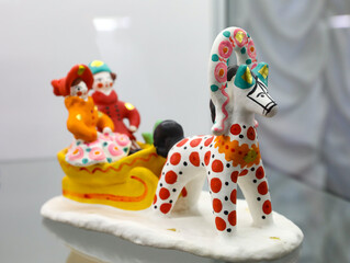 Horse and sled with pair of man and woman in dymkovo painting style with circles. Handicraft toy made by Russian craftsmen in the national traditions of Russia. Dymkovskaya clay toy. Selective focus