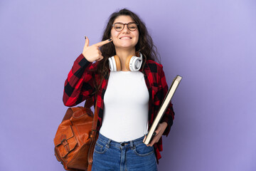 Teenager student isolated on purple background giving a thumbs up gesture