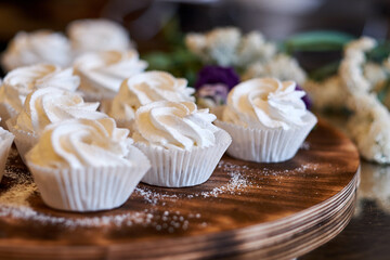 prepared meringues or marshmallows or cupcakes in pastry shop on wooden table
