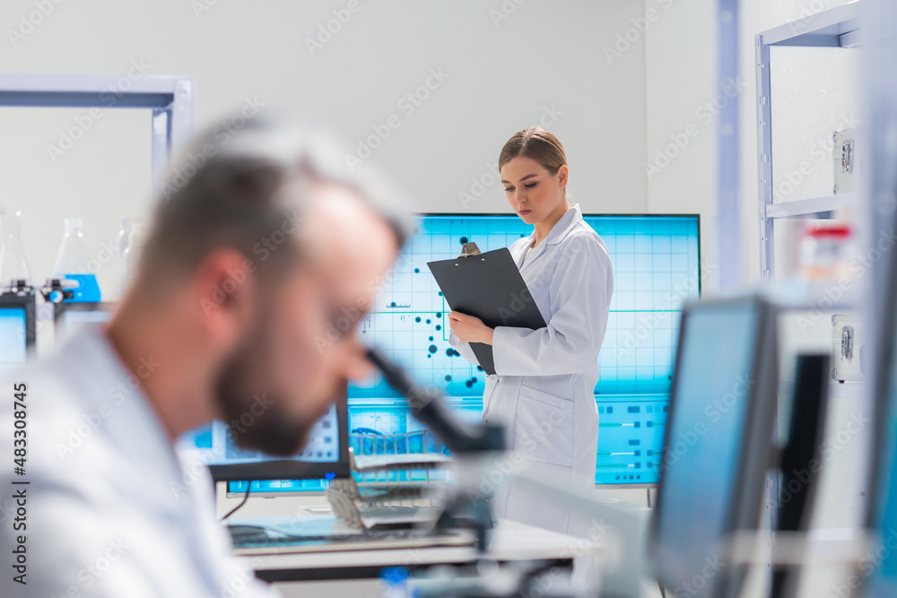 Wall mural Professional team of scientists is working on a vaccine in a modern scientific research laboratory. Genetic engineer workplace. Future technology and science.