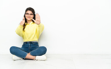 Teenager Russian girl sitting on the floor counting six with fingers