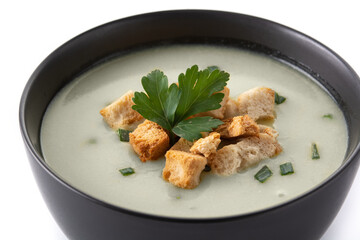 Garlic soup topped with croutons in black bowl isolated on white background