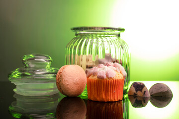 macaroon and cupcake on the table on a dark background near the jars for sweets