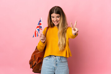 Young blonde woman holding an United Kingdom flag isolated on white background smiling and showing...