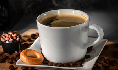 White cup and saucer of espresso coffee close-up on a dark background. Black espresso coffee.