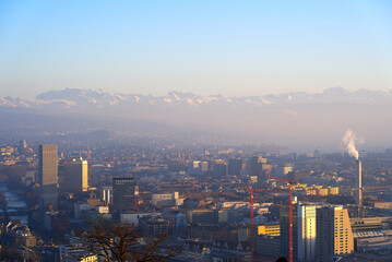 Aerial view over City of Zürich with the Swiss Alps and hazy sky in the background on a sunny winter afternoon. Photo taken January 26th, 2022, Zurich, Switzerland.