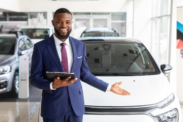Handsome Black Manager In Suit Posing At Workplace In Car Dealership Center