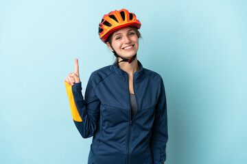 Young cyclist woman isolated on blue background showing and lifting a finger in sign of the best - obrazy, fototapety, plakaty