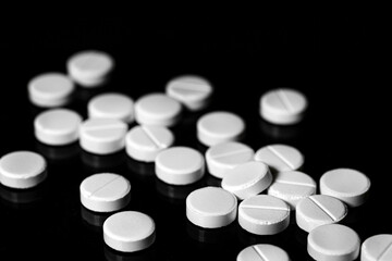 Obraz na płótnie Canvas Close up of white painkiller tablet on a reflective black background