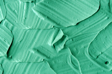 Green cosmetic clay (kelp facial mask, face cream, spirulina body wrap) texture close up, selective focus. Abstract background with brush strokes.