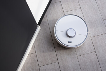 Robot vacuum cleaner removes dust in room on floor. Vacuum cleaner in ordinary apartment. modern...