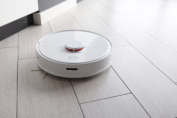 Robot vacuum cleaner removes dust in room on floor. Vacuum cleaner in ordinary apartment. modern...