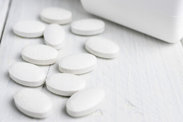 White pills at white wooden planks, medication treatment, close-up view