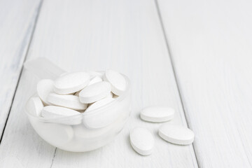 Fototapeta na wymiar White pills in a plastic spoon, medication treatment, close-up view