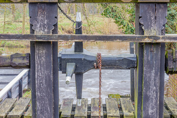 Structure to open the floodgates on the weir next to the Leumolen or Sint-Ursulamolen watermill on the Leubeek river, vegetation in the background. Leudal nature reserve, Midden-Limburg, Netherlands