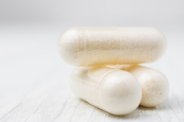 White pills or capsules at white wooden planks, medication treatment, alternative medicine, close-up view