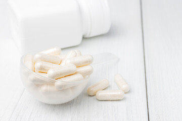 White pills or capsules in a plastic spoon, medication treatment, alternative medicine, close-up view