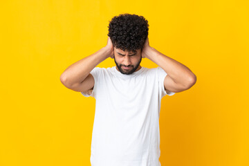 Young Moroccan man isolated on yellow background frustrated and covering ears