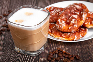 A cup of branded coffee in a scene of coffee beans and a wooden table top. Preparation of cappuccino.