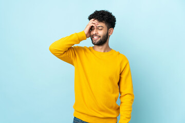 Young Moroccan man isolated on blue background smiling a lot