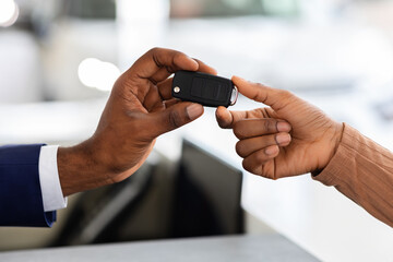 Closeup Of Car Seller Giving Keys To Black Female Customer In Showroom