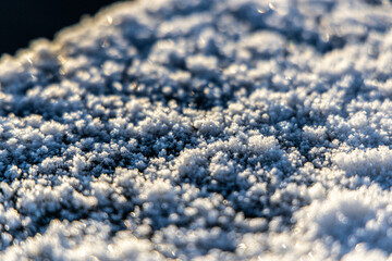 ice cristal in the morning sun, snow flakes on a ground golden lighted