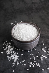 Flake sea salt in a bowl on dark background