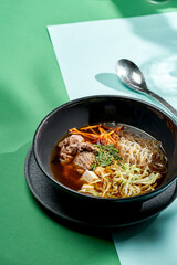 Asian pho bo soup with beef, tofu, noodles and onions in a plate of bright backgrounds. Selective focus, hard light