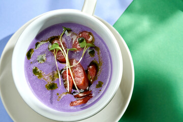 Cream soup of cabbage with smoked sausages in a plate with bright backgrounds. Selective focus, hard light