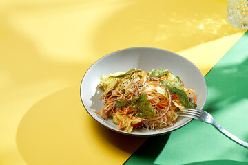 Asian salad with carrots, cabbage and sesame in a plate with bright backgrounds. Selective focus, hard light