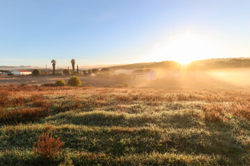 View of typical Alentejo landscape with Portuguese village in morning fog an rising sun at the Rota...