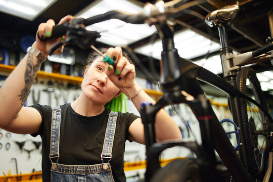 Content woman repairing bike in workshop