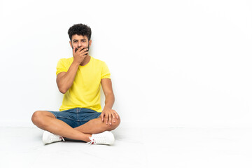 Young Moroccan handsome man sitting on the floor over isolated background surprised and shocked while looking right