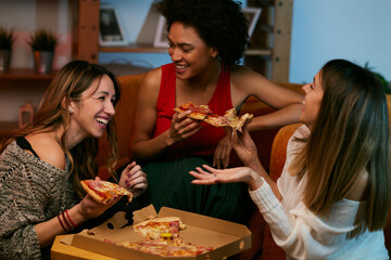 Happy multicultural female friends having party at home and eating pizza. - 483326138