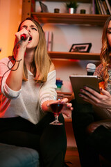 Talented girls with beautiful voices sit at home and sing a duet at karaoke night.