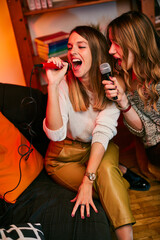 Talented girls with beautiful voices sit at home and sing a duet at karaoke night.